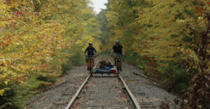 2 bicyclists riding on abandoned railroad tracks