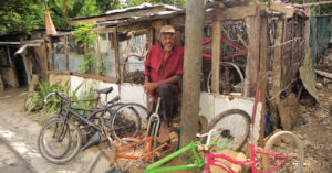 Elderly man standing in doorway with bicycles on the walk