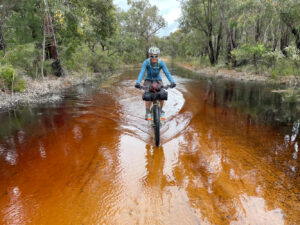 Bicyclist riding through big puddles on the trail