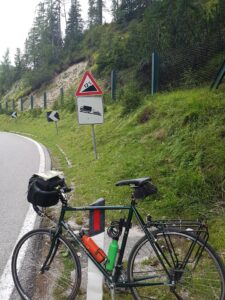 Bicycle parked on roadside in front of steep hill sign