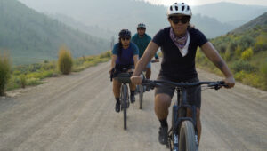 3 people bike riding on a mountain road