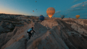 bicycle rider on mountain trail with hot air balloons in the background