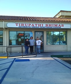 Three people posing in front of an Indian restaurant