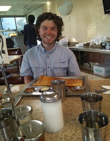 Man sitting a table eating large Indian meal