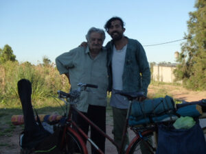 2 men posing in front of a loaded bicycle