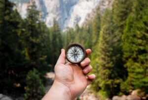 Hand holding a compass in the woods