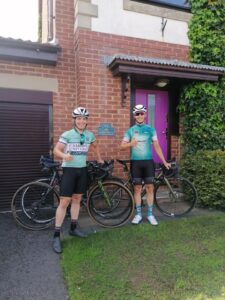 2 touring bicyclists standing in front of a home