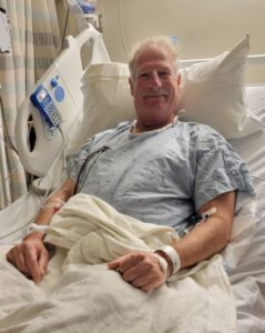 Man lying in hospital bed smiling
