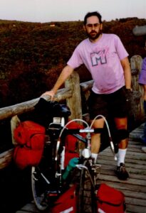 Man with fully loaded touring bicycle standing on a bridge