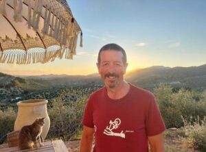 Man standing in front of mountains with the sun setting in the background