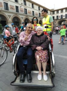 An older couple being pushed in a double wheelchair