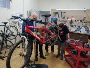 3 men working on a bicycle in a bike shop