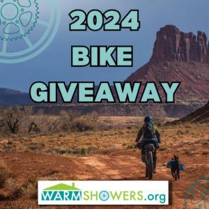A man riding a bicycle with his dog on a desert trail with words: 2024 Bike Giveaway, Warmshowers.org