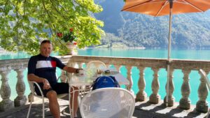 Man sitting at a patio table in front of a beautiful lake