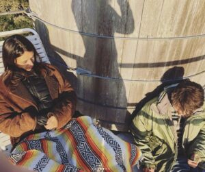 2 women posing on the top of a wooden water tower.