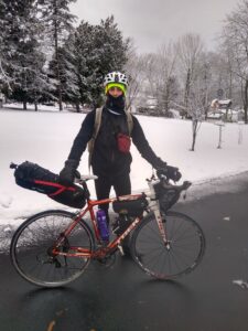 Man dressed for winter standing on the road with his touring bicycle