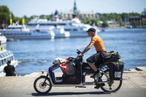 A man riding a bike with a dog in the front trailer