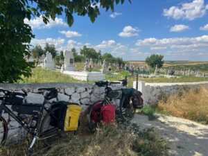 2 loaded touring bicycles propped against a stone wall in front of a cementary