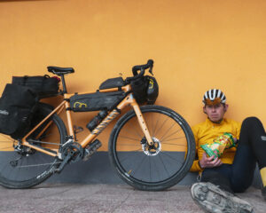 man sitting next to loaded touring bicycle