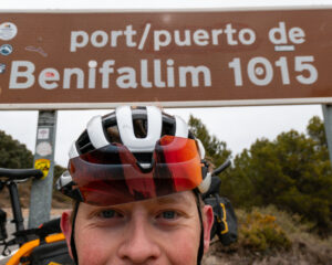 man in bicycle helmet standing in front of a road sign