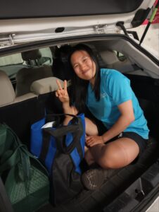 A woman sitting in the back of an SUV flashing the peace sign.