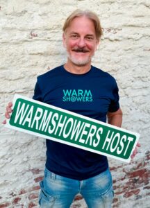 A man holding a Warmshowers Host street sign