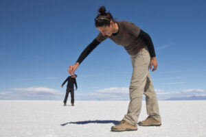 Exaggerated tall women holding a man between her finger tips