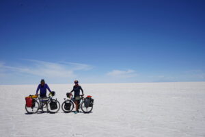 Two people posing with their loaded touring bicycles on a desert flat