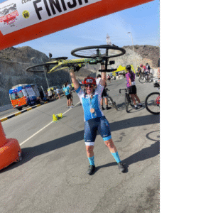 Cyclist posing with bike overhead at the finish line