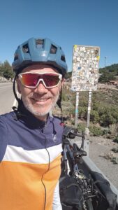 Man with his touring bicycle standing in front of a sticker covered road sign