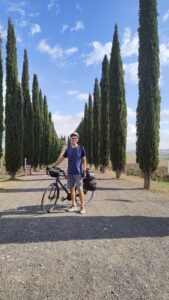Man standing with his touring bicycle on a tree lined path in the countryside
