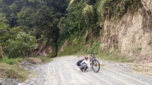 A person on an empty road working on a broken bicycle