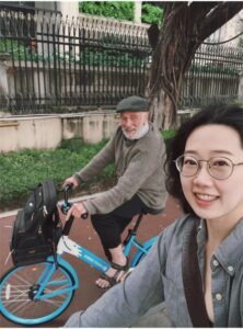 Man and woman biking down a treed lane.