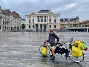 Man with a loaded tandem touring bicycle standing in a city square