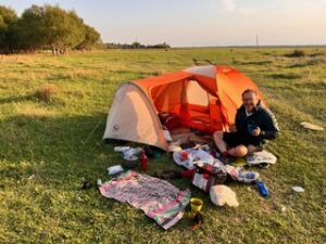 Man pitching a tent to camp in a field