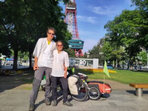 man and woman posing with their bicycle in front of a tower
