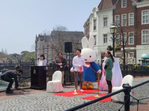 Man, woman, and bunny character unveiling a sculpture