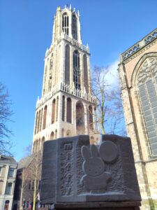 Stone sculpture in front of an old stone tower building