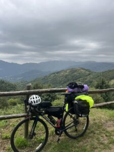 Loaded touring bicycle propped against a fence overlooking a mountain range