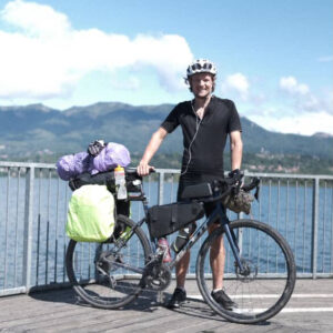 Man standing with his touring bicycle in front of a lake