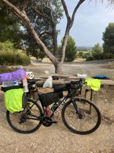 A loaded touring bicycle parked in front of a picnic table
