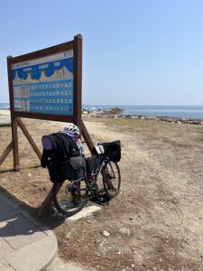 A bicycle leaning against an informational sign by the sea