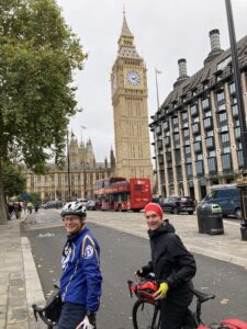 2 men on bicycles on a street in front of Big Ben in London