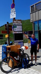 Man standing in front of directional signs with his bicycle