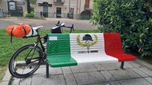 Park bench painted as the Italian flag with a bicycle behind it
