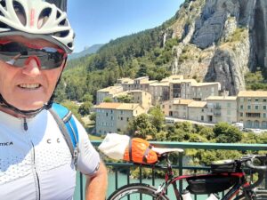 Man with his bicycle overlooking a lake and a village
