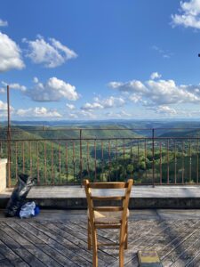 An empty chair sitting on a balcony overlooking a valley