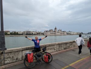 A woman standing on a bridge with her bicycle overlooking a city