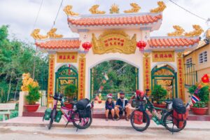 Two people and their touring bicycles sitting under a Chinese pagoda
